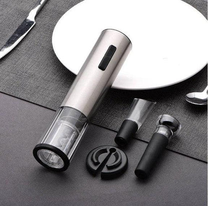 Abrebotellas eléctrico de vino con base transparente y accesorios sobre mantel gris junto a plato blanco
