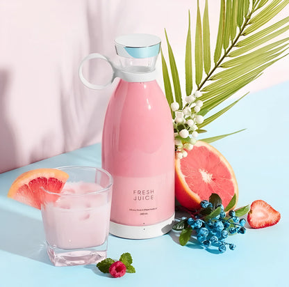Botella rosa de jugo fresco con vaso, rodaja de pomelo, frutas y hojas verdes sobre fondo azul y rosa